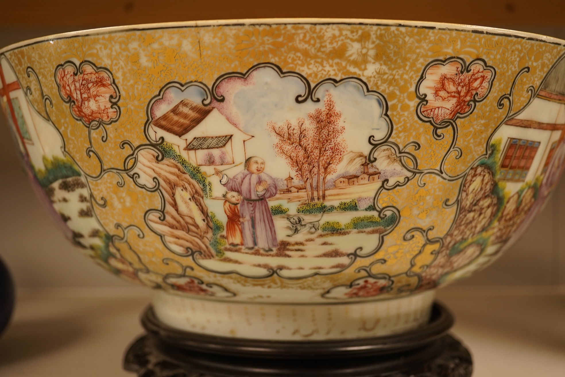 An 18th century Chinese famille rose figural bowl, on wooden stand, 34cm diameter.